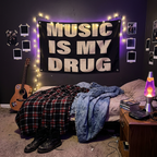 Music Is My Drug tapestry above an unmade bed in a Y2K grunge bedroom with string lights, plaid blanket and guitar
